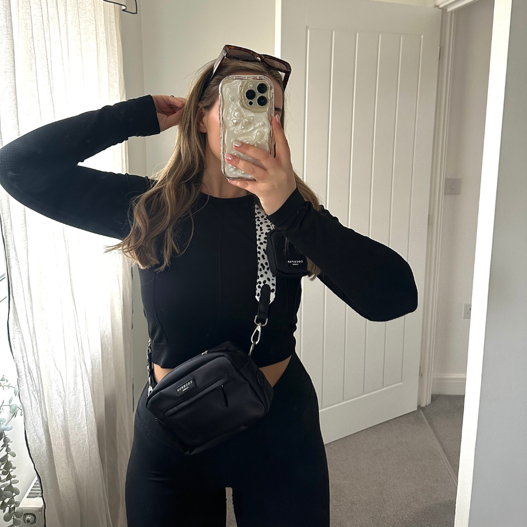 Person taking a mirror selfie wearing a black outfit and sunglasses on their head.