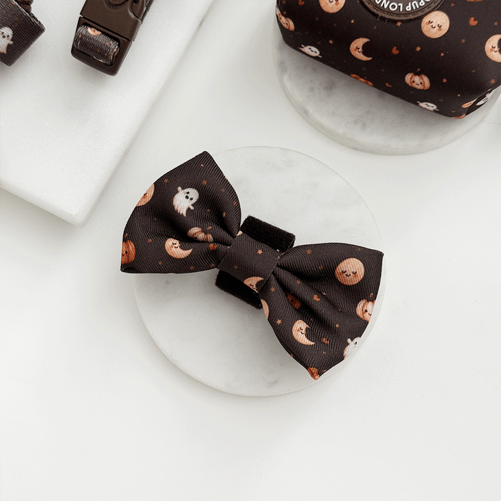 Brown dog bow tie with cute Halloween print featuring pumpkins, ghosts, and moons.