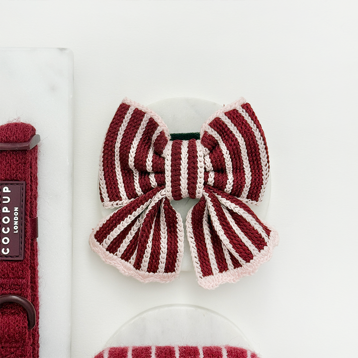 Fabric dog bow with burgundy and baby pink vertical stripes and a light pink scalloped edge.