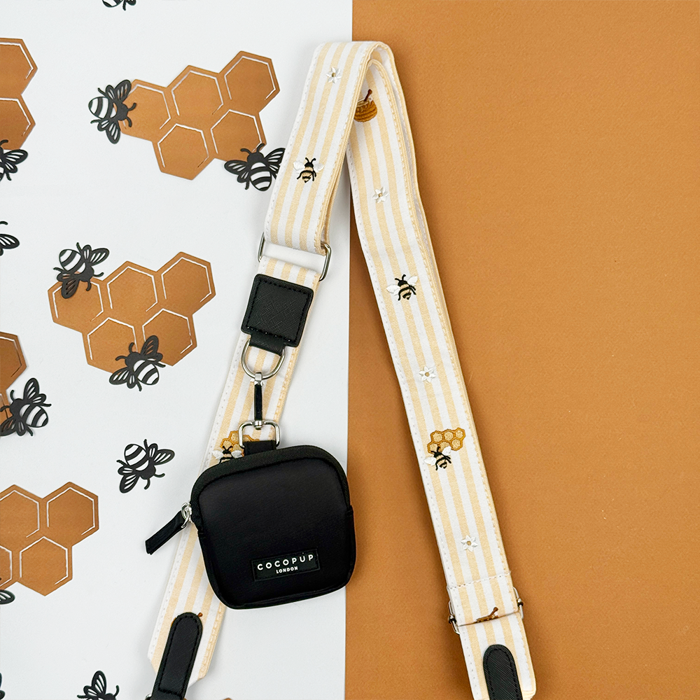 Pale yellow and white striped Bag Strap with bee and honeycomb embroidered decals. Attached is a Cocopup Treat Pouch in black.