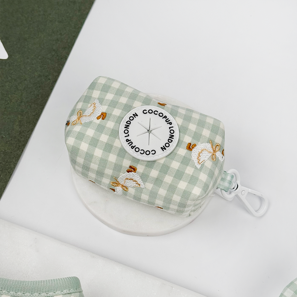 Green and white check print poop bag holder with dispensing hole, with embroidered geese design.