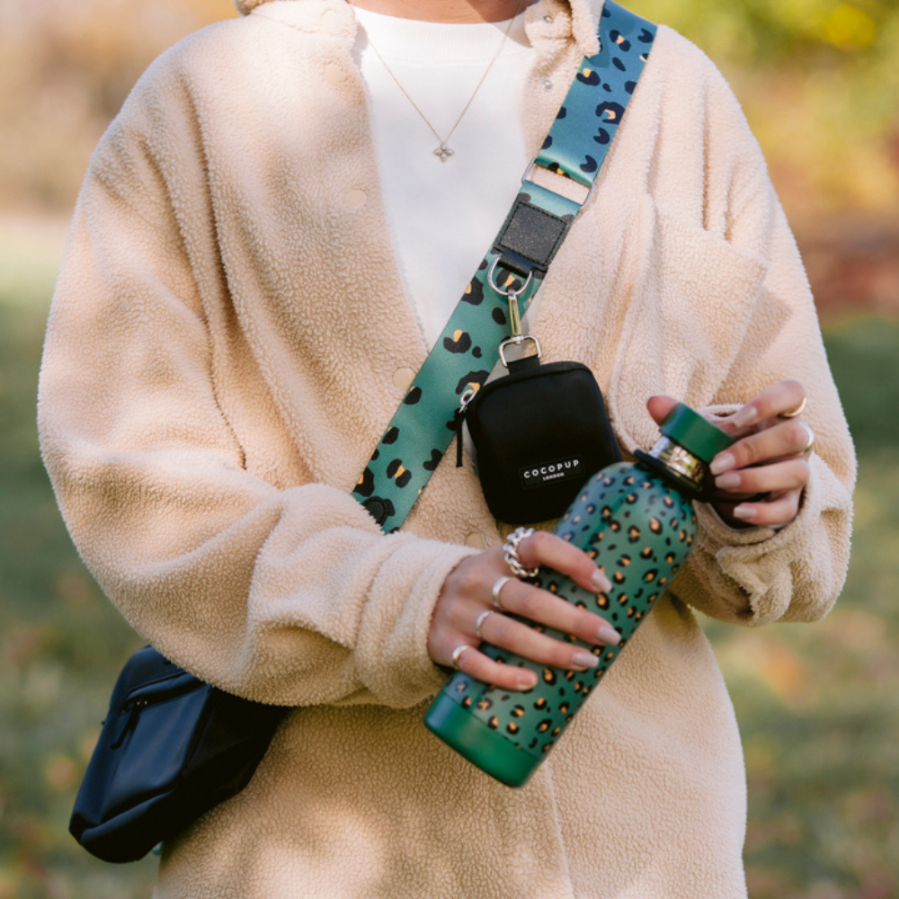 Person wearing beige fleece holding a green leopard-print water bottle.